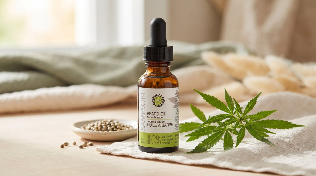 Amber dropper bottle of Sampson hemp beard oil on a pale wooden surface beside a small ceramic dish of hemp seeds and a green hemp leaf in soft window light