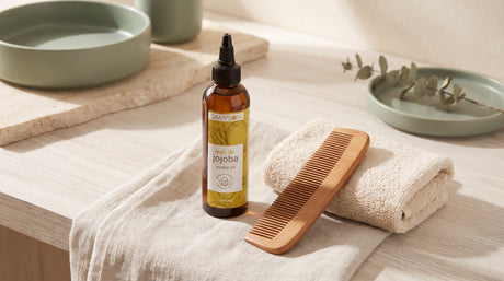 Pure Jojoba Oil bottle beside a wooden beard comb - Sampson Eco Shop