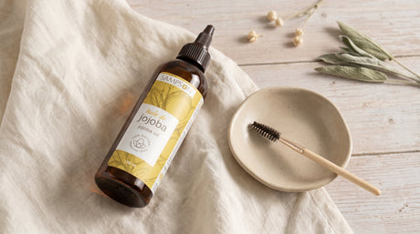 Pure Jojoba Oil bottle styled for lash and eye-care use, editorial eco-luxury scene