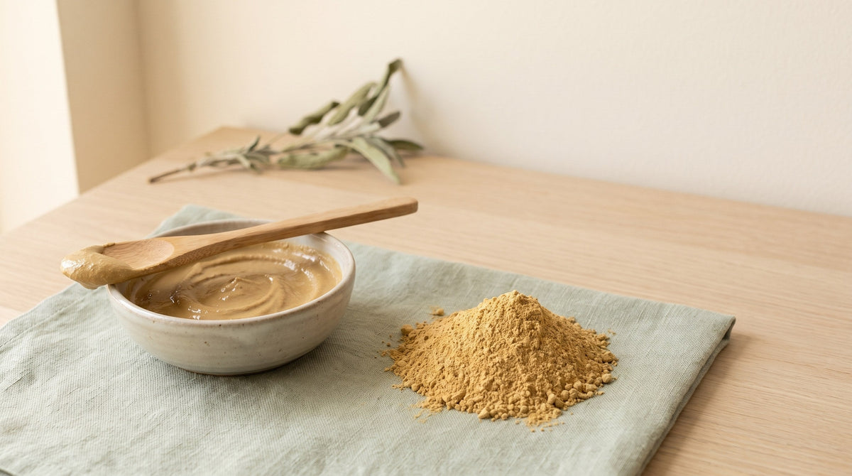 Sampson multani mitti clay powder beside a bowl of smooth clay face pack paste and a wooden spoon on linen